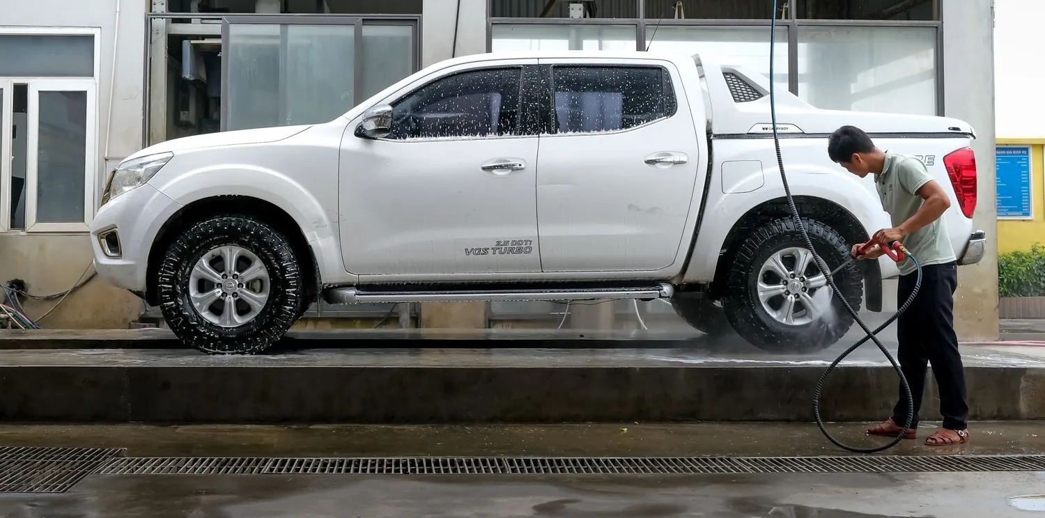 A pickup being rinsed down under a wash bay canopy.
